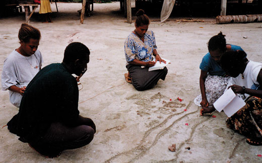 pla-mud_map Development workers make an impromptu map in the sand to make decisions about training at Mana'abu village, Manu Lagoon, Malaita island, Solomon Islands. Kastom Gaden Association, TerraCircle projects.